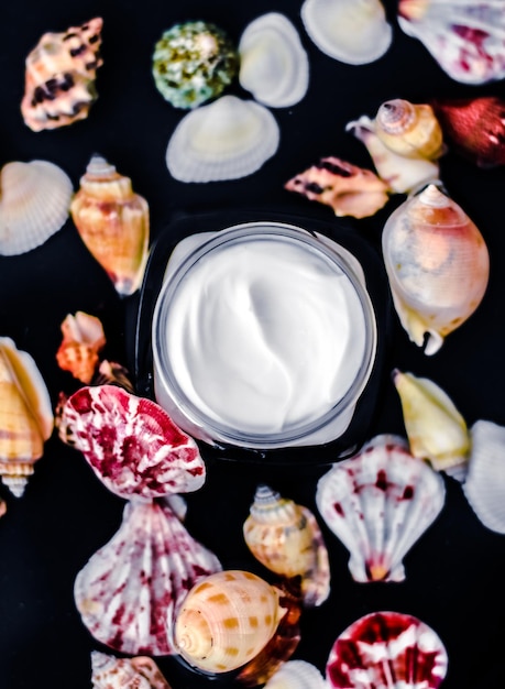 水と海の貝殻の背景に高級アンチエイジ化粧品に敏感なスキンケアモイスチャライザービューティーフェイスクリーム