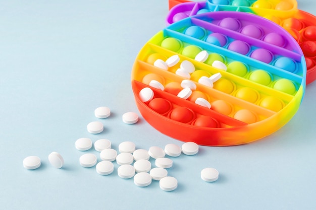 Sensory toy Poppit and pills on blue background