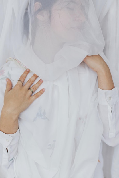 Sensual beautiful woman posing under soft white fabric modern veil Mental health Bridal morning