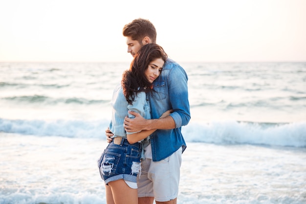 Sensual beautiful young couple standing and hugging on the beach