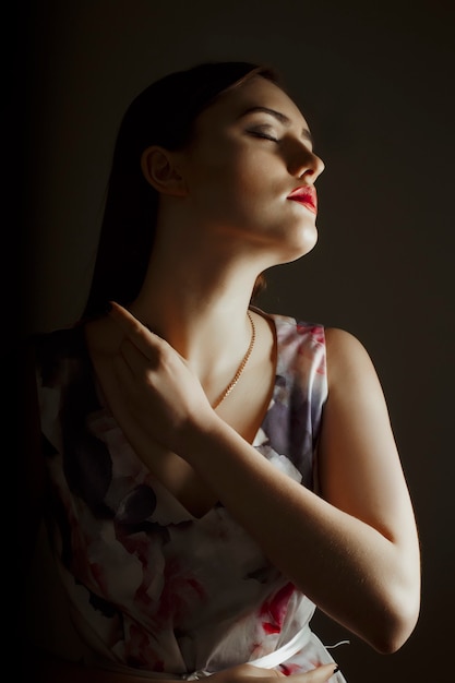 Sensual brunette woman in dress posing in the dark room