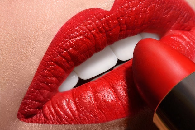 Sensual open mouth with red tube of lipstick