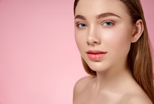 sensual, pretty, young girl with pink, nude lips and well groomed skin of face posing on pink