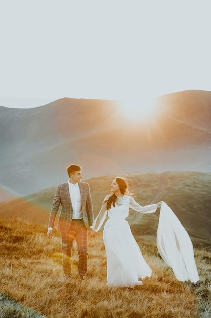 Sensual wedding couple groom and bride in a long white dress standing on the edge of the mountains