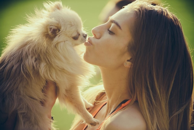 Foto donna sensuale bacia un simpatico cucciolo di spitz, animale domestico