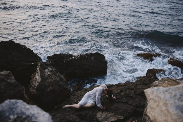 Sensual woman lying on rocky coast with cracks on rocky surface\
landscape