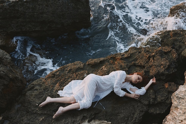 Sensual woman lying on rocky coast with cracks on rocky surface\
landscape