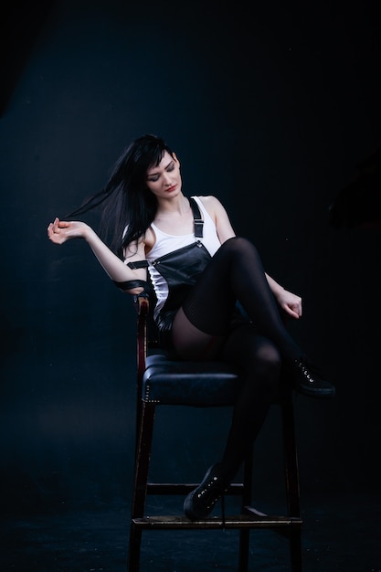 Sensual woman posing on a chair in black studio