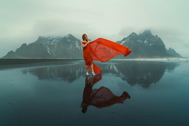 Reynisfjara 해변 경치 사진에 빨간 옷을 입은 관능적 인 여자