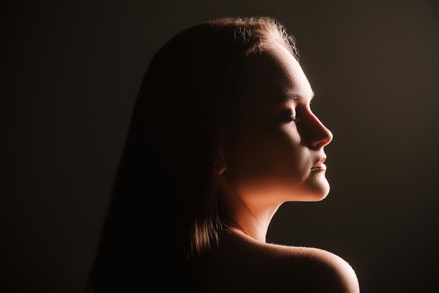 Sensual woman silhouette. Feminine energy. Profile portrait of peaceful lady with closed eyes isolated on dark background. Harmony balance. Aesthetic cosmetology.