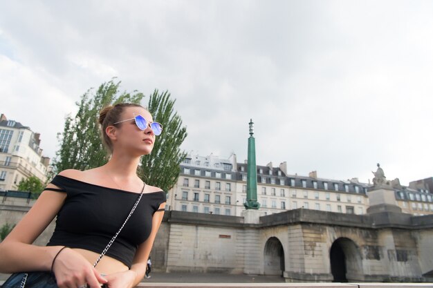 Sensual woman wear sunglasses on cityscape. Woman in sexy vest in paris, france. Wanderlust or vacation and travelling concept. Summer fashion and style.