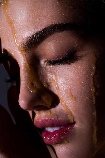 꿀 방울과 관능적인 젊은 여자 얼굴 얼굴에 꿀 드립으로 섹시 한 모델을 닫습니다