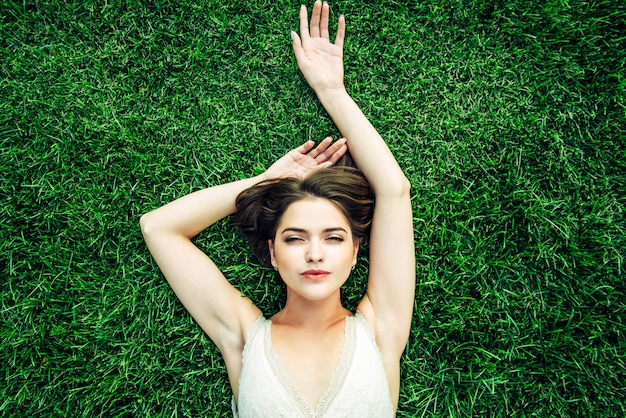 写真 緑の芝生の上にある軽いドレスの官能的な若い女性