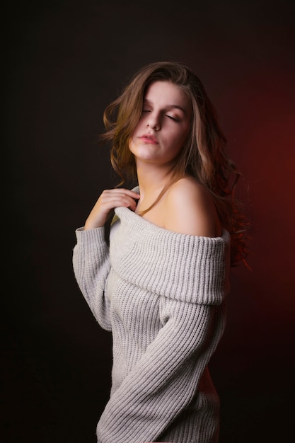 Sensual young woman posing in sweater with naked shoulders