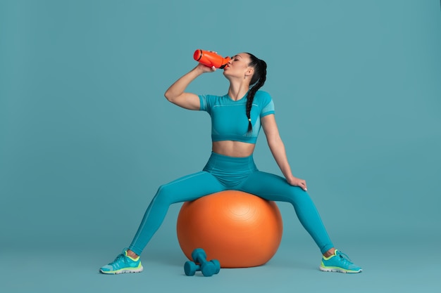 Sensueel. Mooie jonge vrouwelijke atleet beoefenen, zwart-wit blauw portret. Sportief fit brunette model met fitball. Body building, gezonde levensstijl, schoonheid en actie concept.