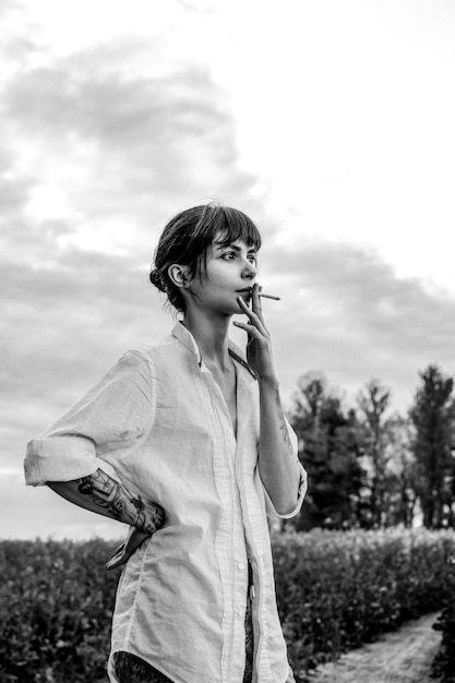 Sensueel portret van een mooie vrouw met een sigaret en donkerbruine ogen tussen een koolzaadveld.