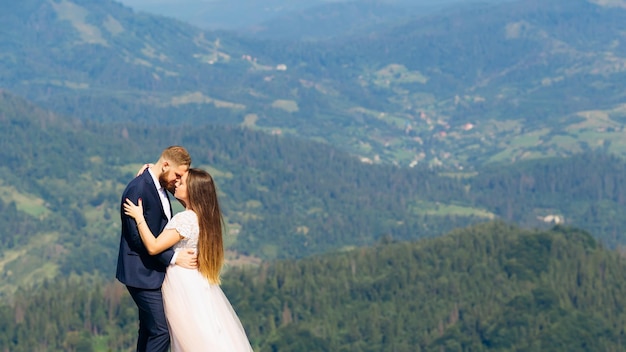 Sensuele knuffels jonggehuwden tegen de achtergrond van fantastische bergen met groene bossen