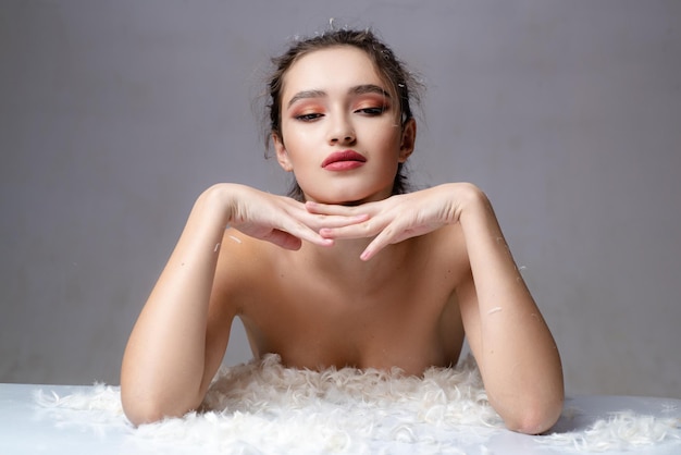 Sensuele vrouw in witte pluizige veren. Goedemorgen. zoete dromen. zachte huid. huidverzorgingsconcept. cosmetica en make-up. trendy uitstraling. make-up en haarstijl. Schoonheid en mode. Sexy meisje. zachte veren