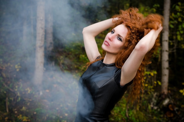 Sensuele vrouw met rood krullend haar op een bos