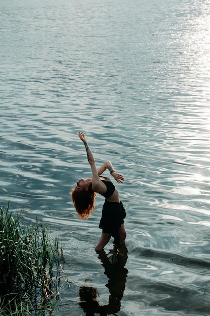 Sensuele wilde vrouw die een rituele sjamanistische vrije dans danst tussen de golven bij zonsondergang.