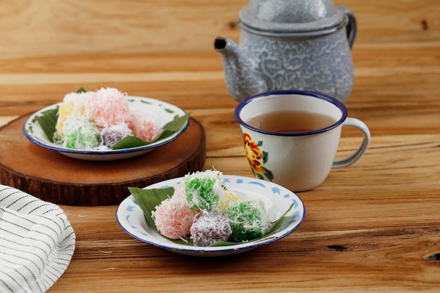 Photo sentiling or ongolongol steamed grated cassava with food coloring coated with grated coconut served with tea