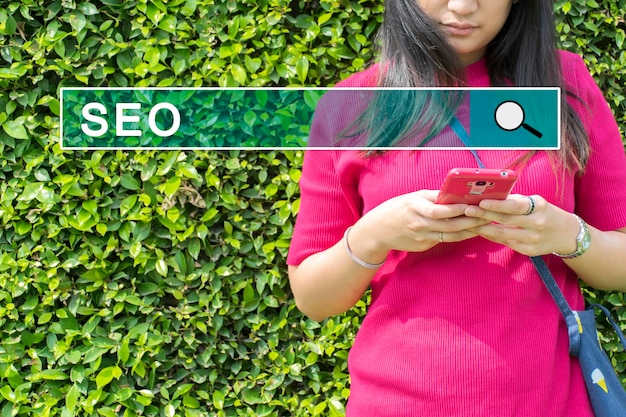 Foto seo concept vrouwen die ontspanning voelen vind informatie op haar smartphone de achtergrond is groene bladeren door search engine optimization om effectieve informatie te krijgen