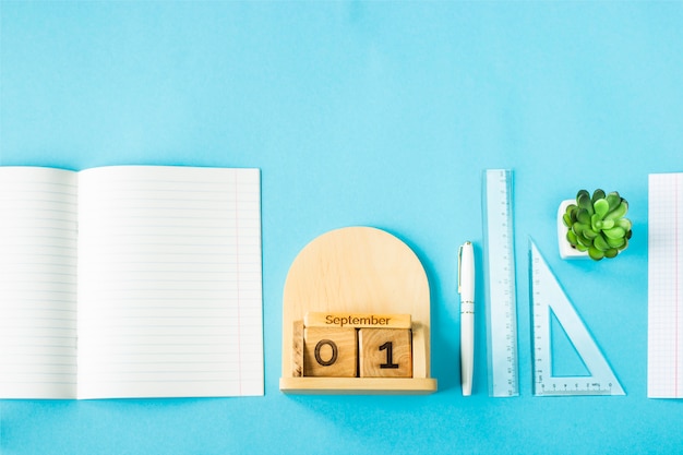 September 1 on a wooden calendar among the supplies for study on a blue background