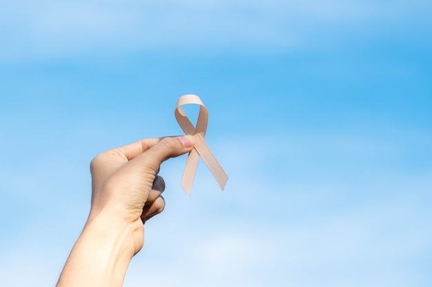 Settembre mese della consapevolezza del cancro uterino, mano della donna che tiene il nastro di pesca per sostenere le persone che vivono e le malattie. concetto di assistenza sanitaria e giornata mondiale del cancro