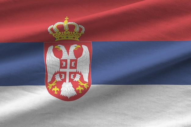 Serbia flag with big folds waving close up under the studio light indoors The official symbols and colors in banner