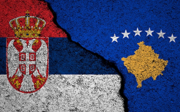 セルビアとコソボ共和国の旗の背景ひびの入った壁軍事紛争と戦争のコンセプト写真