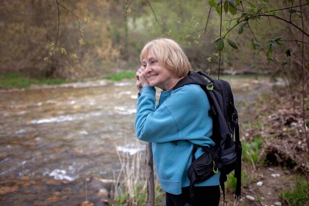 Фото Спокойная пожилая женщина у ручья в лесу момент спокойного размышления