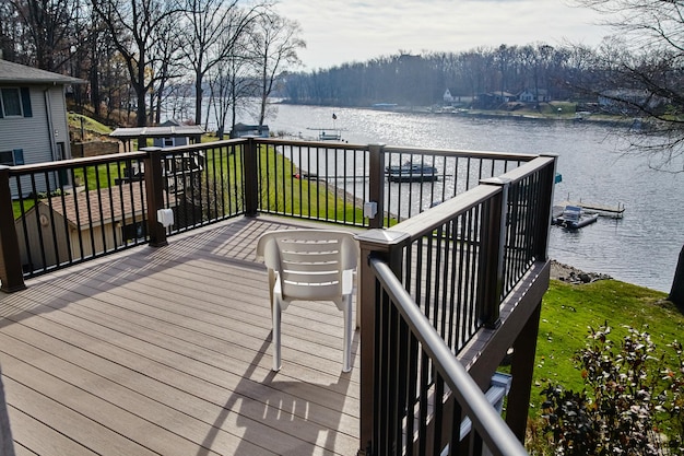 Photo serene lakeside wooden deck with chair and boats elevated view