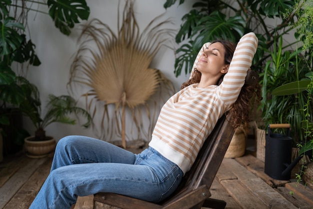 Foto serene ontspannen jonge vrouw met gesloten ogen die armen ontspannen in het interieur van de stedelijke jungle