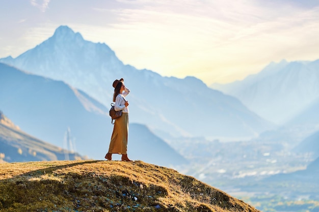 Serene peaceful girl traveler backpacker wearing hat standing alone and enjoying freedom and calm traveling