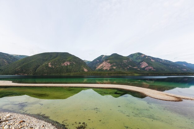 Serene scene by the mountain lake in Canada with reflection of the rocks in the calm water.