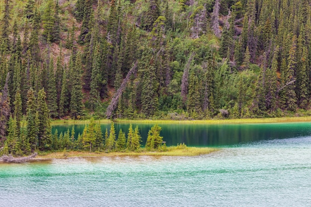 Serene scene by the mountain lake in Canada with reflection of the rocks in the calm water.