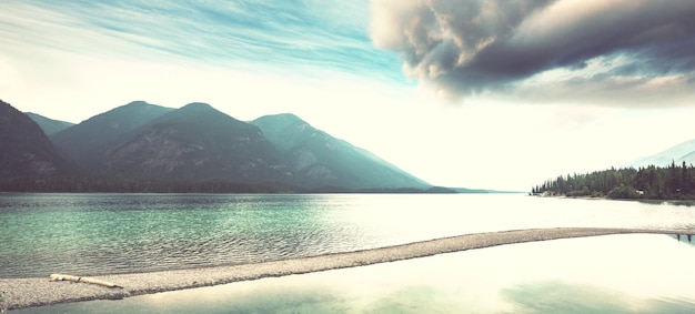 Serene scene by the mountain lake in Canada with reflection of the rocks in the calm water.