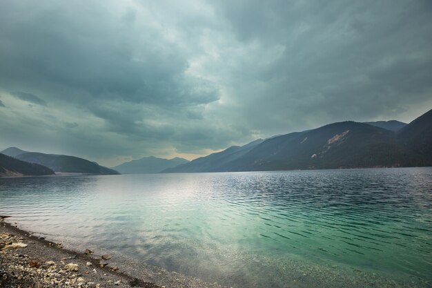 Serene scene by the mountain lake in Canada with reflection of the rocks in the calm water.