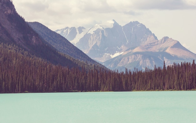 Serene scene by the mountain lake in Canada with reflection of the rocks in the calm water.