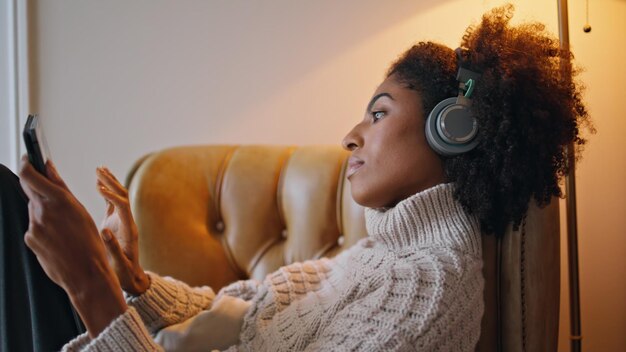 Serene woman browsing tab screen at evening closeup curly girl relaxing home