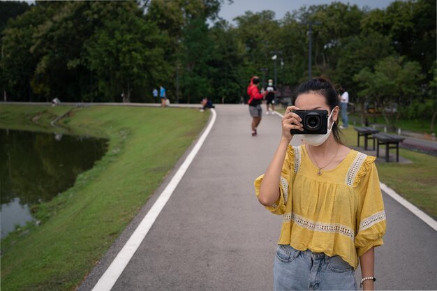 Photo series photo of young women wearing surgical protection mask playing with camera in the evening