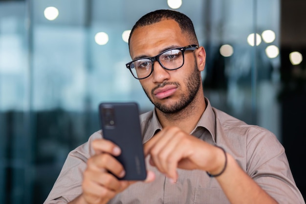 Serieus denkende zakenman close-up man met smartphone en het lezen van nieuws online werknemer binnen