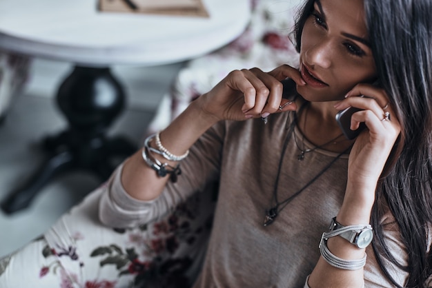 Foto serieus gesprek. mooie jonge vrouw die haar kin met vinger aanraakt en op de slimme telefoon praat talking