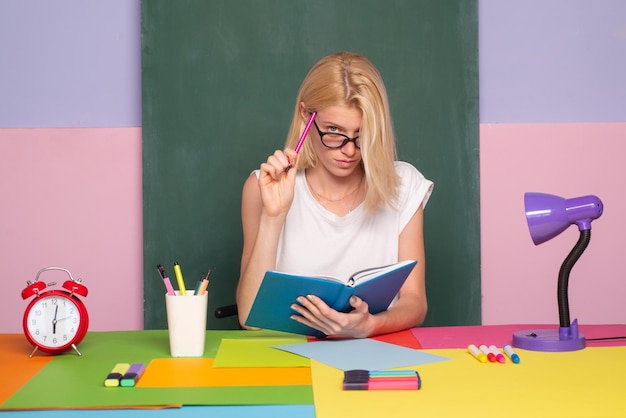 Serieus idee Portret van een leraar die op school denkt Onderwijsconcept Vrouwelijke student die aantekeningen maakt uit een boek in de bibliotheek