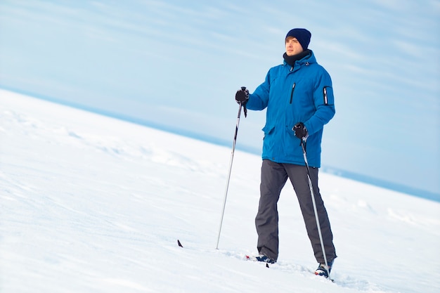 Serieus, jongeman aan het skiën in de winter, gaat bergopwaarts. Man langlaufen, winterpret. Kopieer de ruimte