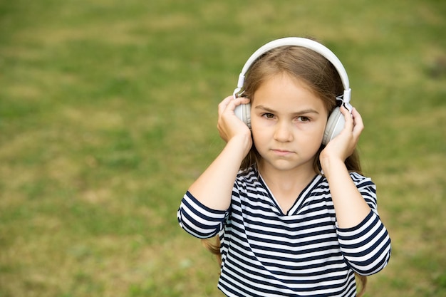 Serieus schattig kind luister naar muziek in koptelefoon zomerlandschap buitenshuis geluid kopieerruimte