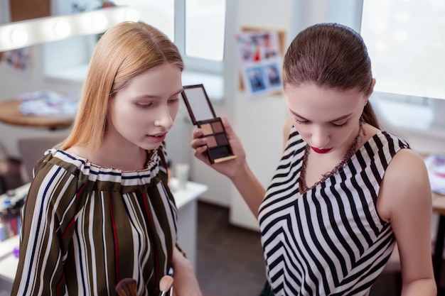 Serieuze aardige vrouwen die samen staan terwijl ze cosmetica voor zichzelf kiezen