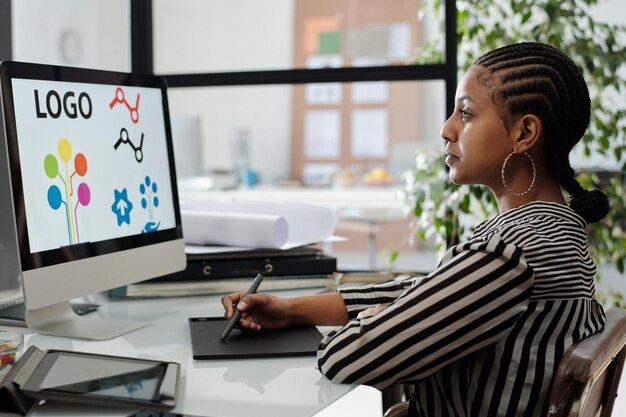 Serieuze Afro-Amerikaanse vrouwelijke webdesigner werkt aan een nieuw project per bureau