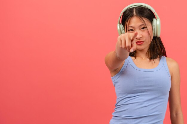 serieuze jonge Chinese vrouw die met haar vinger naar een roze achtergrond wijst