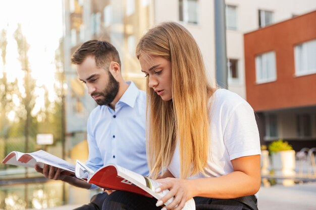 serieuze jonge studentencollega's op straat die studeren met voorbeeldenboeken.